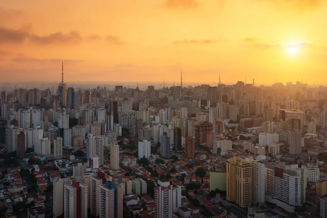 Cobertura: pôr do sol sobre a cidade, com torres de antena no horizonte.